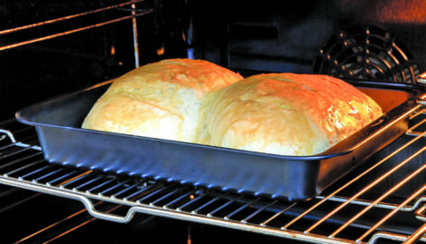 Two loaves of bread cooking together in an oven.